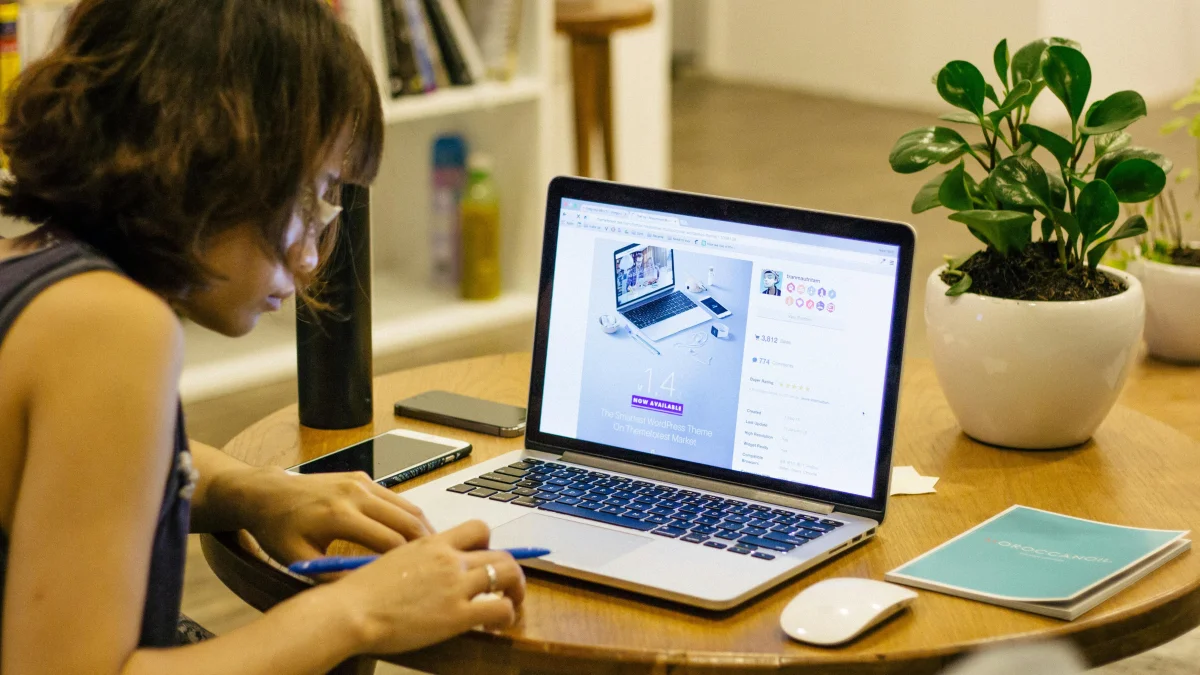 A sitting at a table working on a Macbook