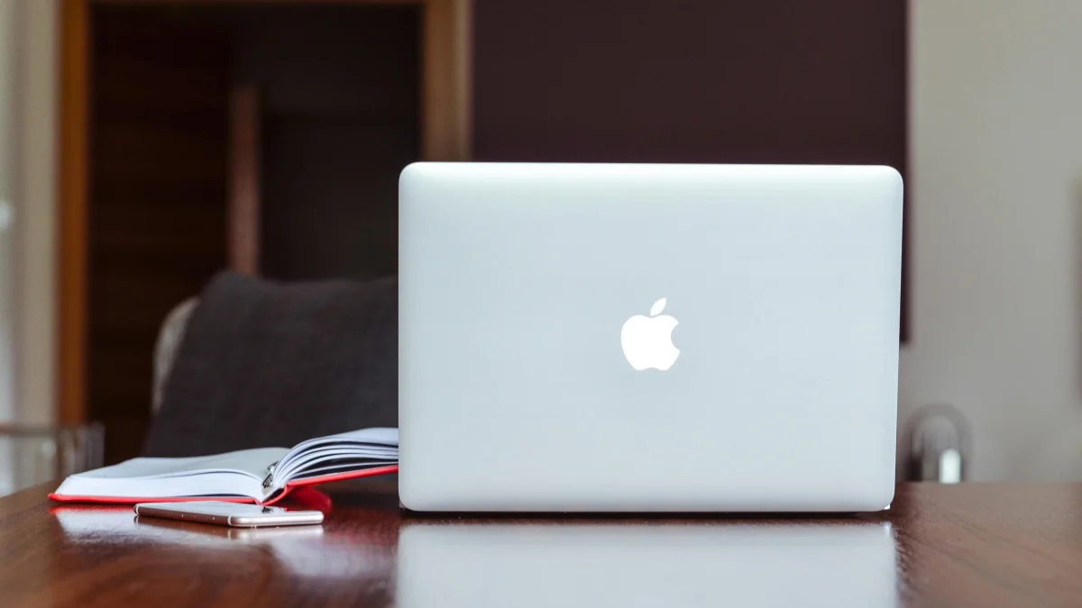 Macbook and a notebook on a wooden table